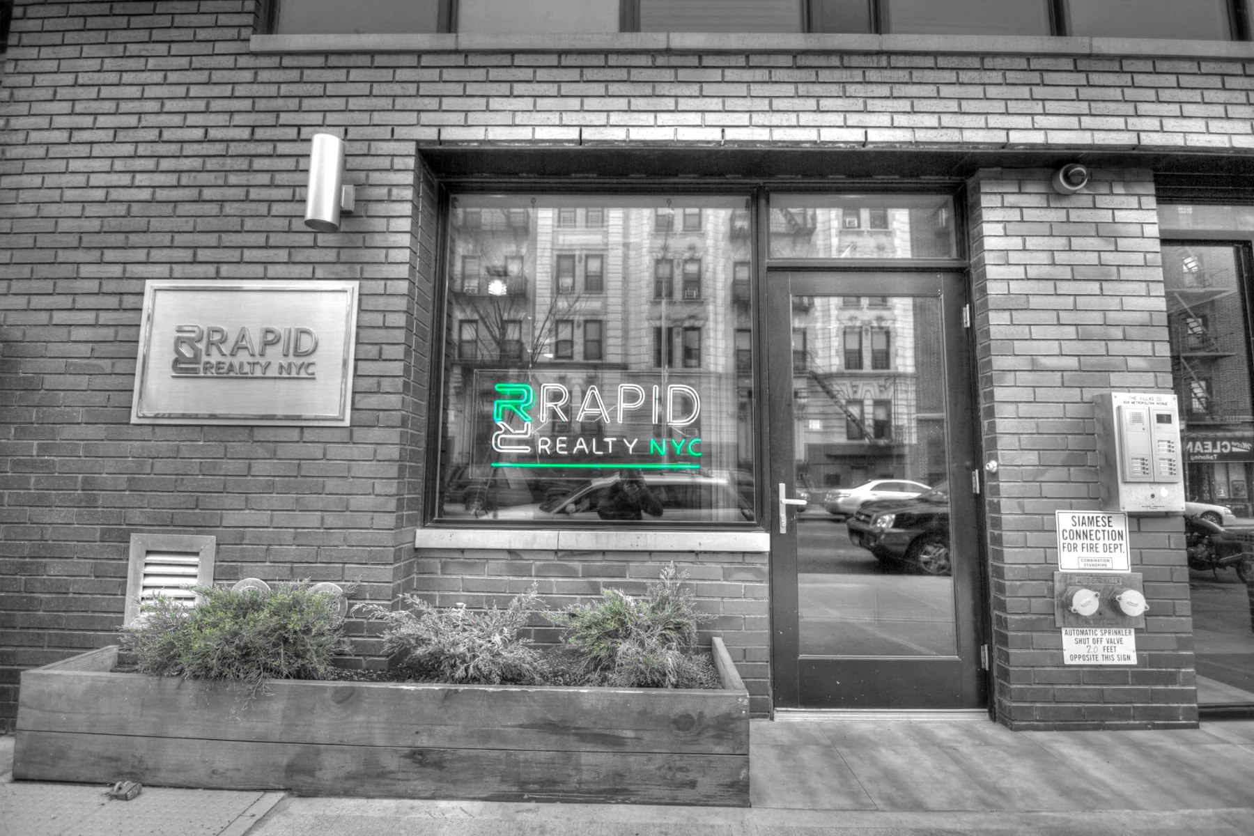 Rapid Realty NYC storefront with its lit green neon sign